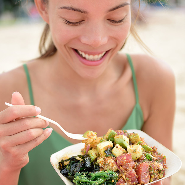 Kvinne spiser poke bowl med laks